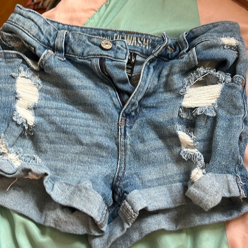 Blue ripped jeans shorts. Two back pockets and two front. Bottoms are rolled up.